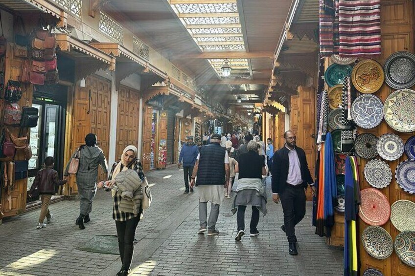 A bustling market with wooden stalls and a variety of colorful plates on display. 3