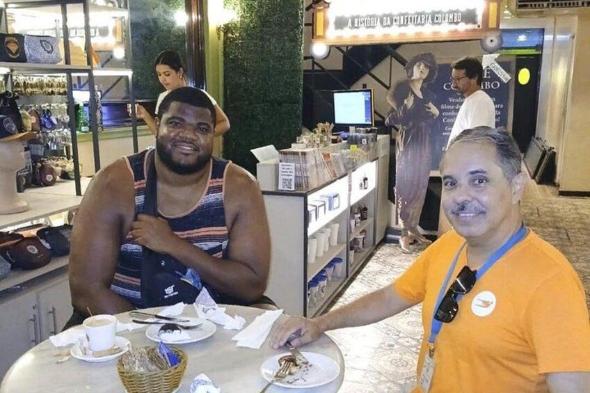 Two people seated at a table with a basket and plates of food. 2