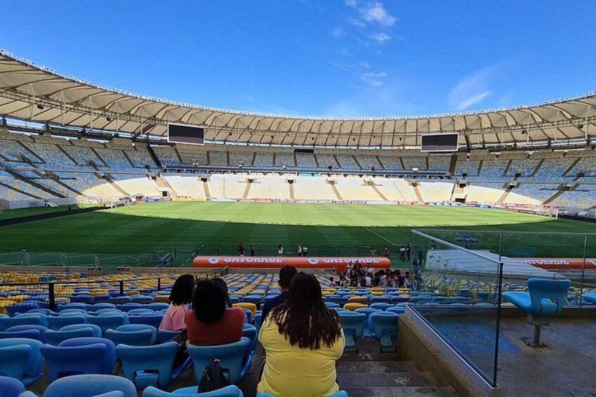 Un estadio con asientos azules, césped verde y cielo despejado. 2