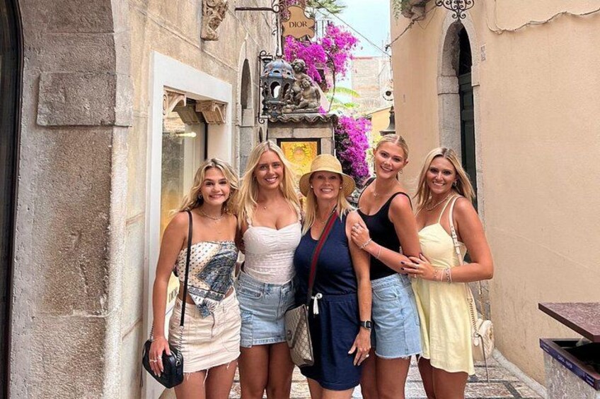 A group of people standing in a narrow street with a building entrance and a statue. 5