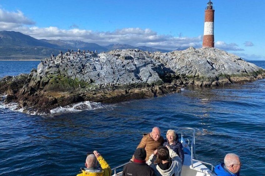 A boat with passengers near a rocky island with a lighthouse. 1