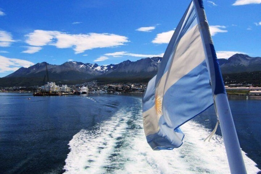 A flag on a boat, a body of water, and mountains in the background. 4