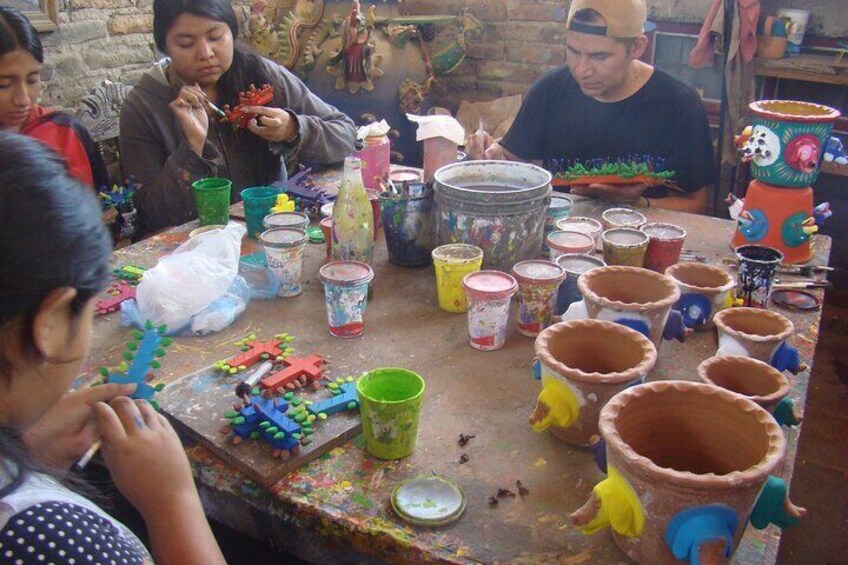 A group of people engaged in pottery making with various clay pots and tools on a table. 5