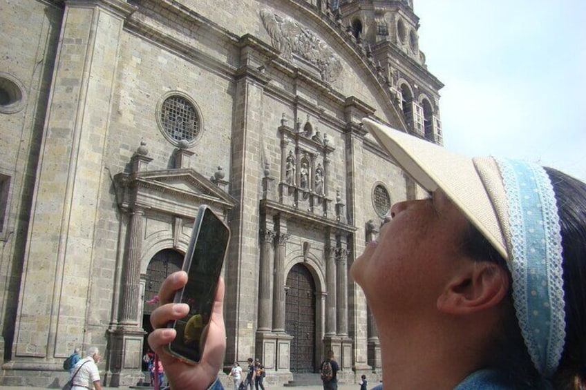 A person taking a photo with a smartphone in front of a historic building with ornate architecture. 1