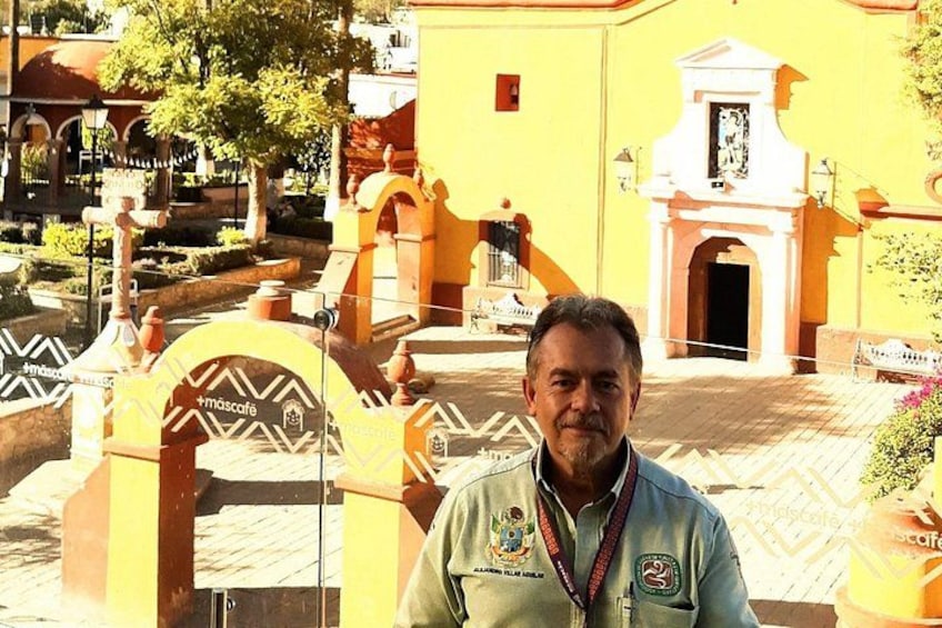 A man standing in front of a yellow building with a white archway and a fountain. 1