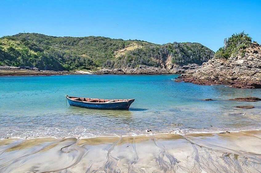 A boat on a clear beach with calm water and a hilly landscape in the background. 5