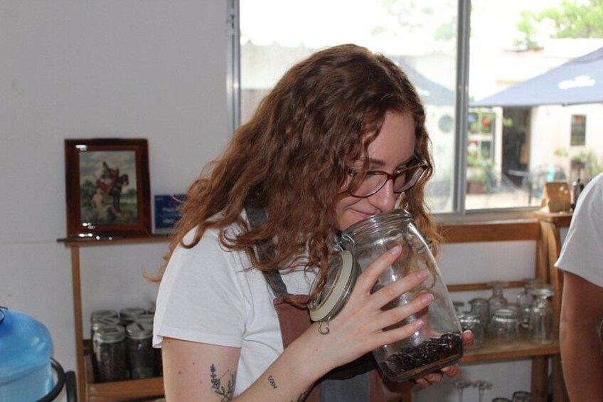 A person holding a jar with a dark liquid, in a room with shelves and a window. 5