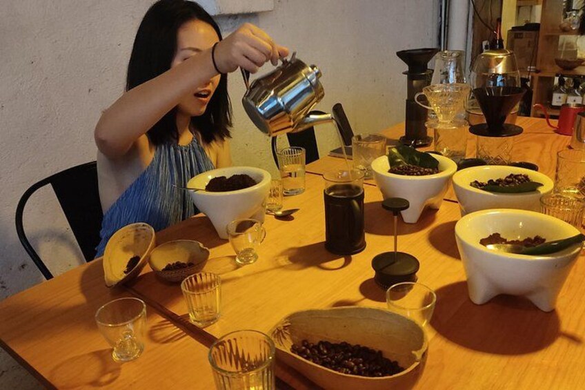 A person pouring coffee into a cup at a table with multiple bowls and glasses. 4