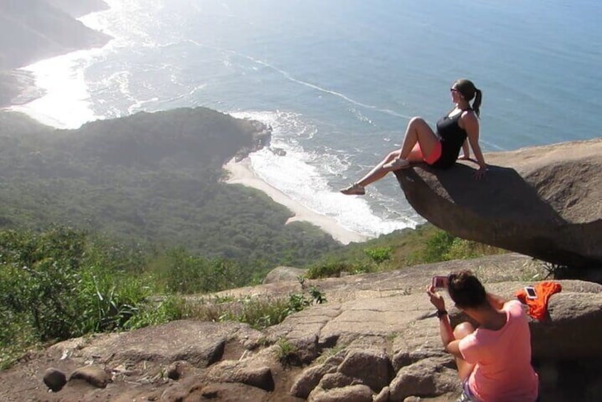 A person sitting on a rock overlooking a coastal landscape. 1