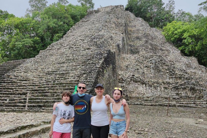A large ancient pyramid with a group of people standing in front of it. 1