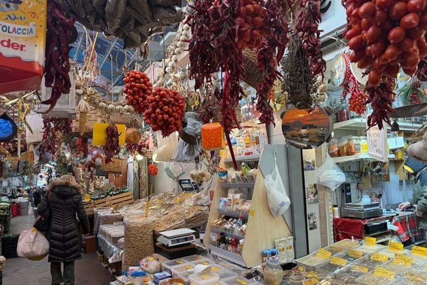 A market with various goods, including hanging red peppers and sacks of grains. 4