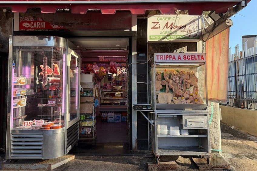A storefront with a sign that reads 'TRIPPA A SCELTA' and another sign that says 'CARNI'. 3