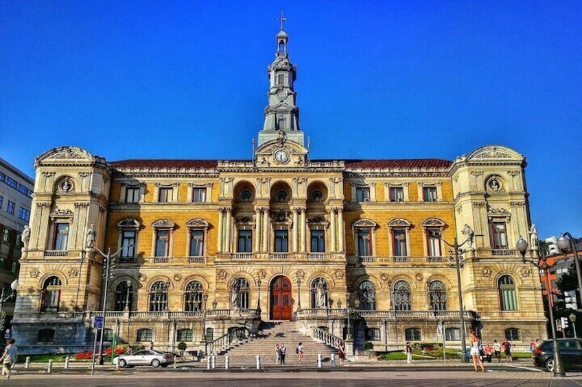 A large, historic building with a prominent clock tower and a red door. 3
