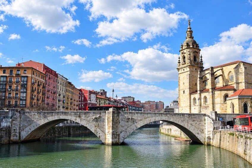 A stone bridge over a river, historic buildings, and a tower with a clock. 3