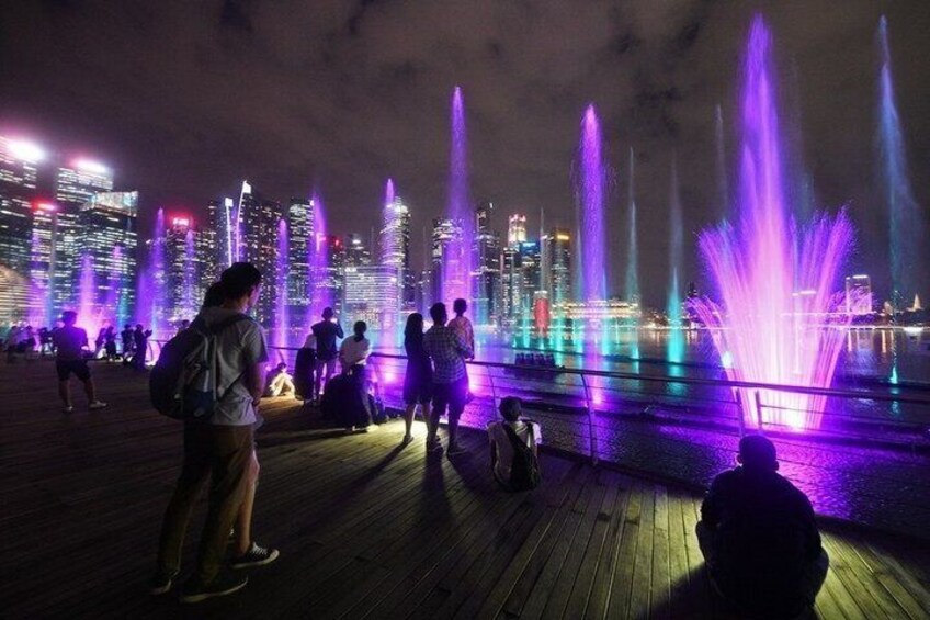 A nighttime cityscape with illuminated fountains and skyscrapers in the background. 5