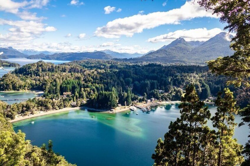 A lake surrounded by forested hills and mountains under a clear sky. 3