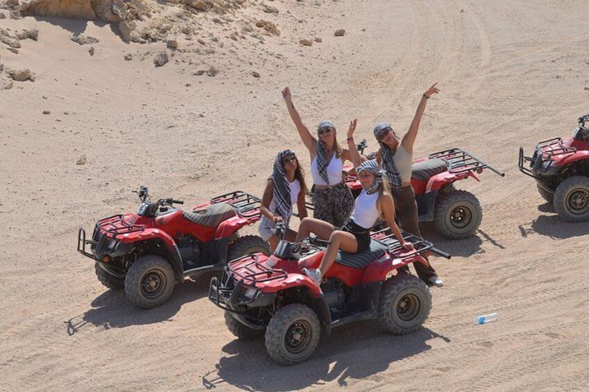A group of people on red ATVs in a desert landscape. 2