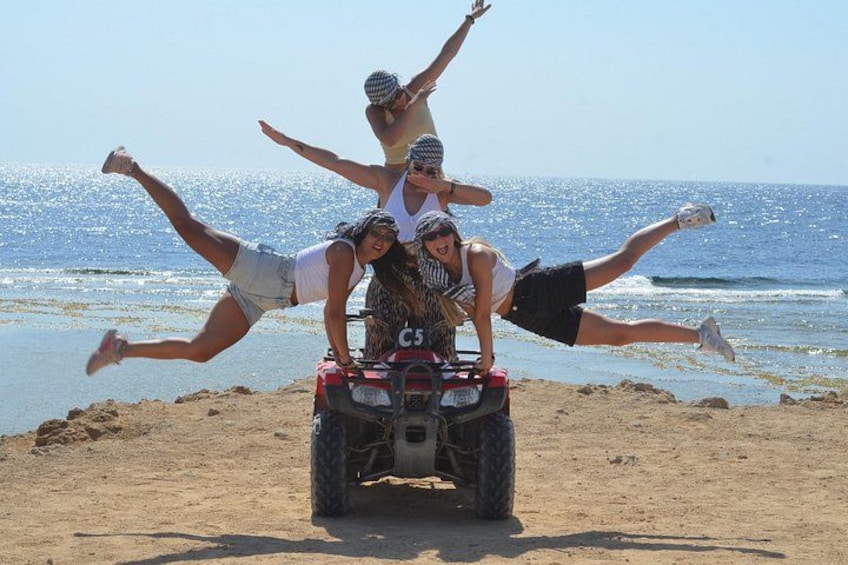 A group of people on a beach with a dune buggy. 1