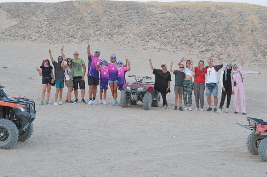 A group of people posing with ATVs in a desert landscape. 5