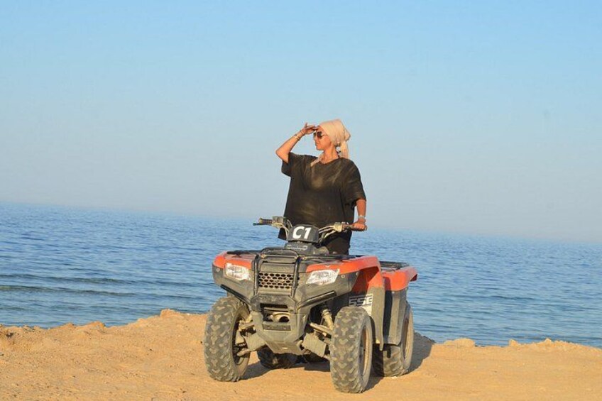 A person on a quad bike near a body of water. 4