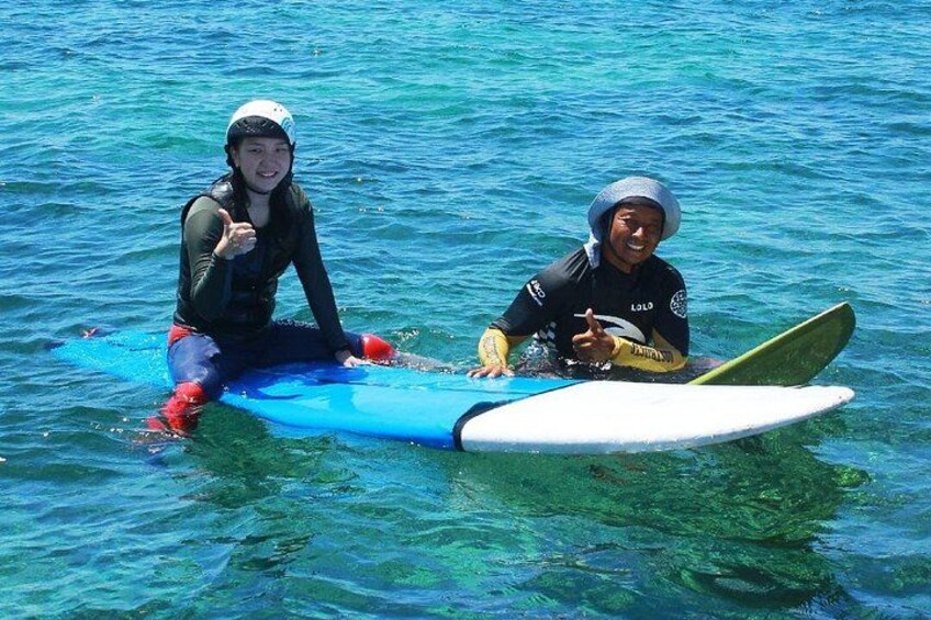 Two people sitting on surfboards in the water. 1