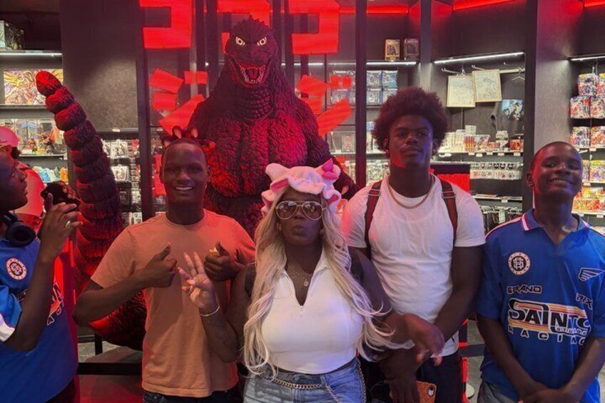 A group of people in a store with a large Godzilla figure in the background. 3