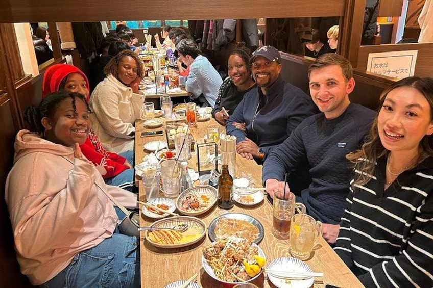 A group of people sitting around a table with food and drinks. 4