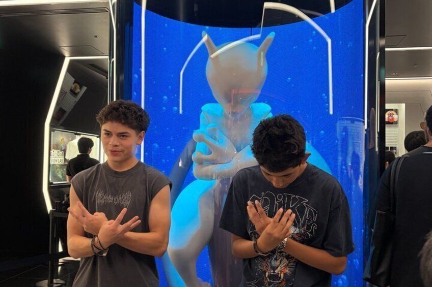 Two people standing in front of a digital display with a blue background and a figure holding a drink. 5