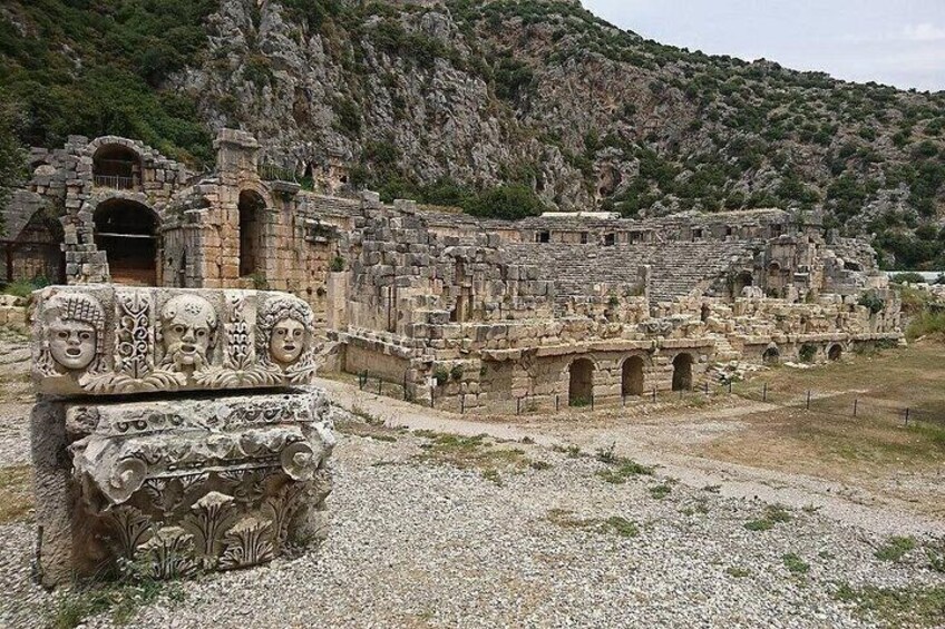 Ancient ruins with stone structures and a carved stone block with faces. 4