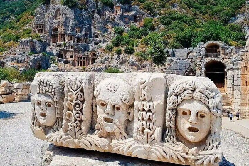 A stone relief with carved faces and a mountainous backdrop. 5