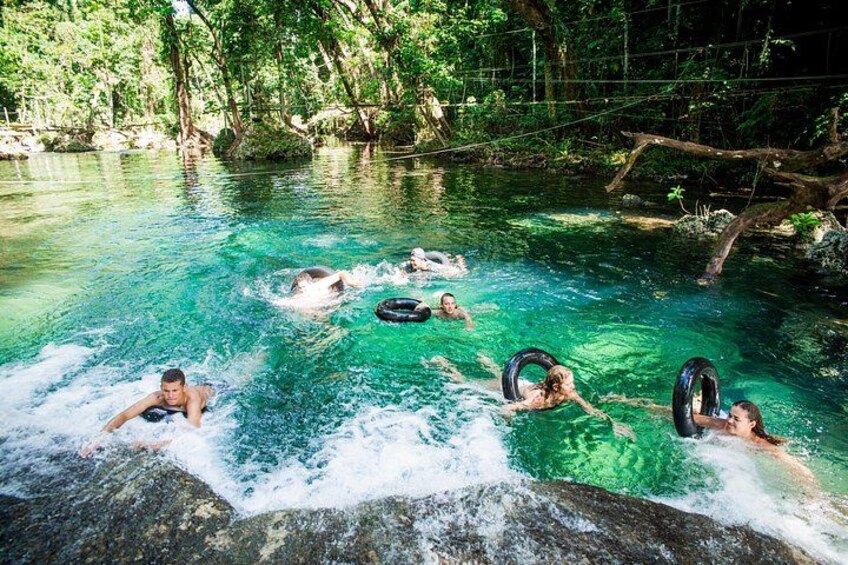 People floating in a clear water body surrounded by trees. 3