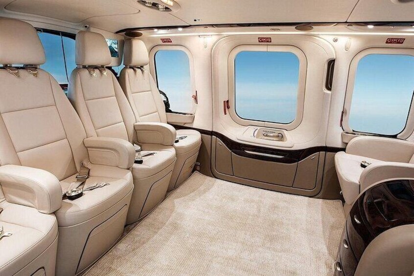 A luxurious interior with beige leather seats, a carpeted floor, and large windows. 2