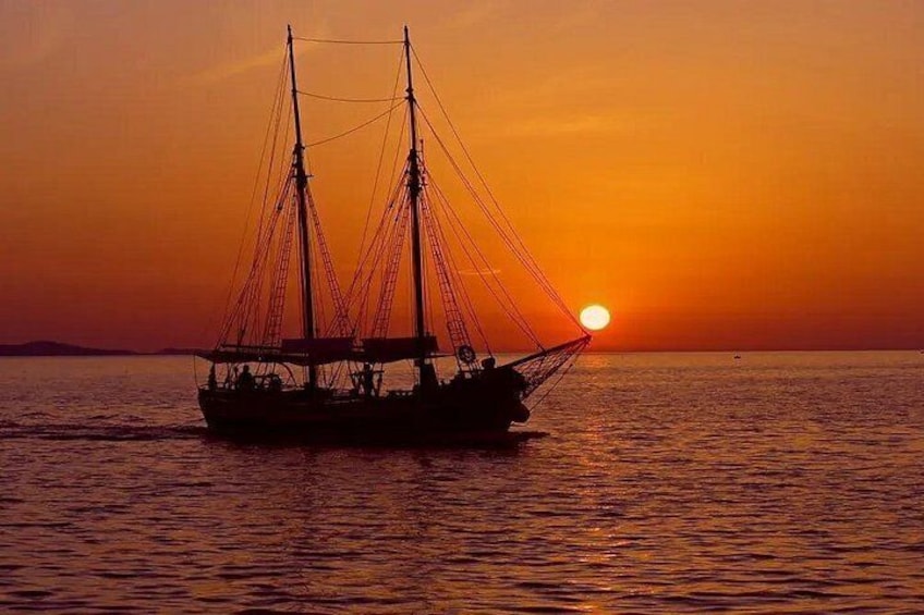 A sailing boat at sunset with the sun setting on the horizon. 1