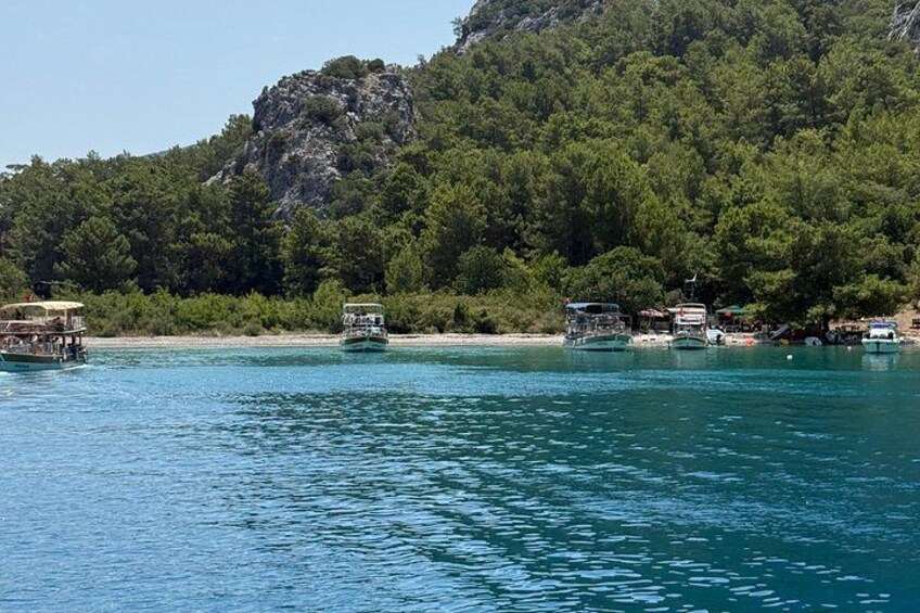 A coastal scene with boats docked near a forested hill. 2