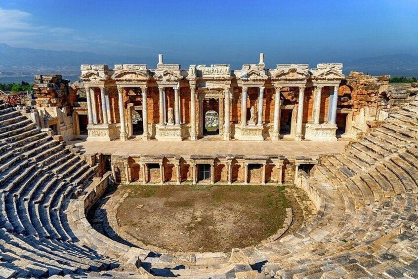 An ancient amphitheater with stone seating and a central stage. 3