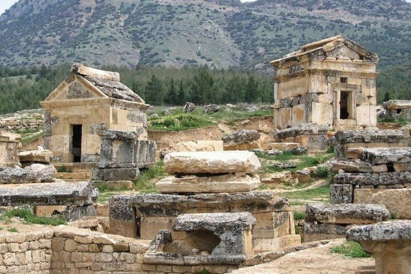 Ancient ruins with stone structures and a mountainous backdrop. 2