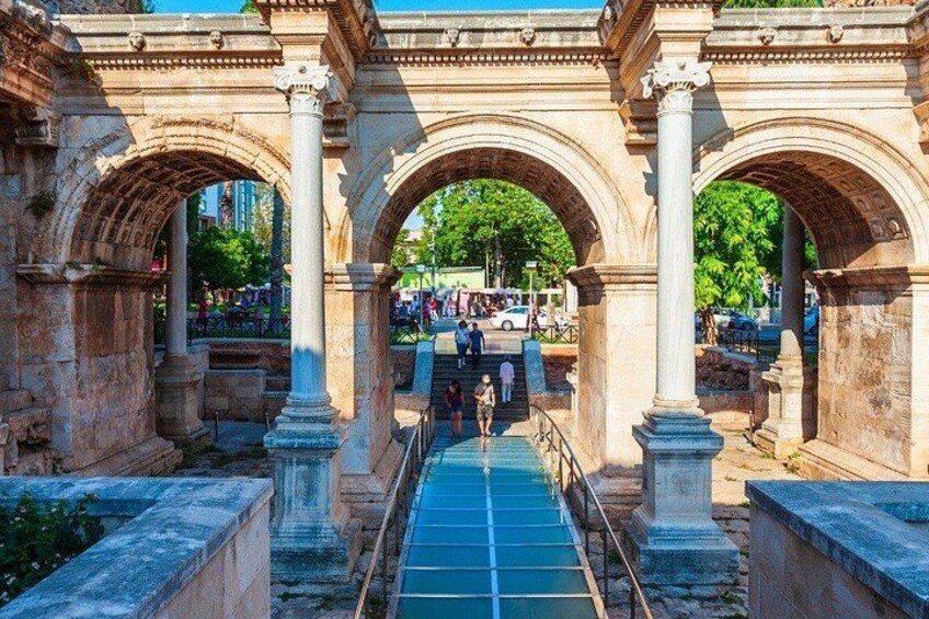An ancient stone archway with columns, a blue pathway, and a modern cityscape in the background. 5