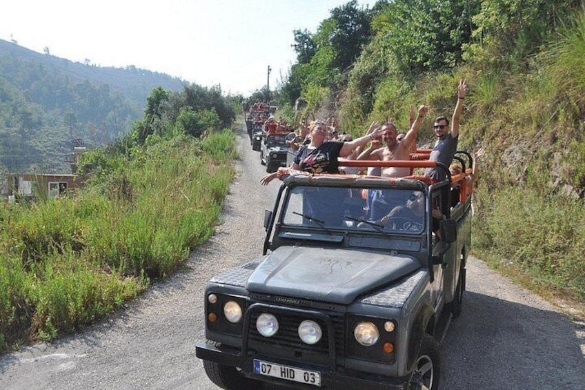 A convoy of vehicles on a narrow road surrounded by greenery. 5