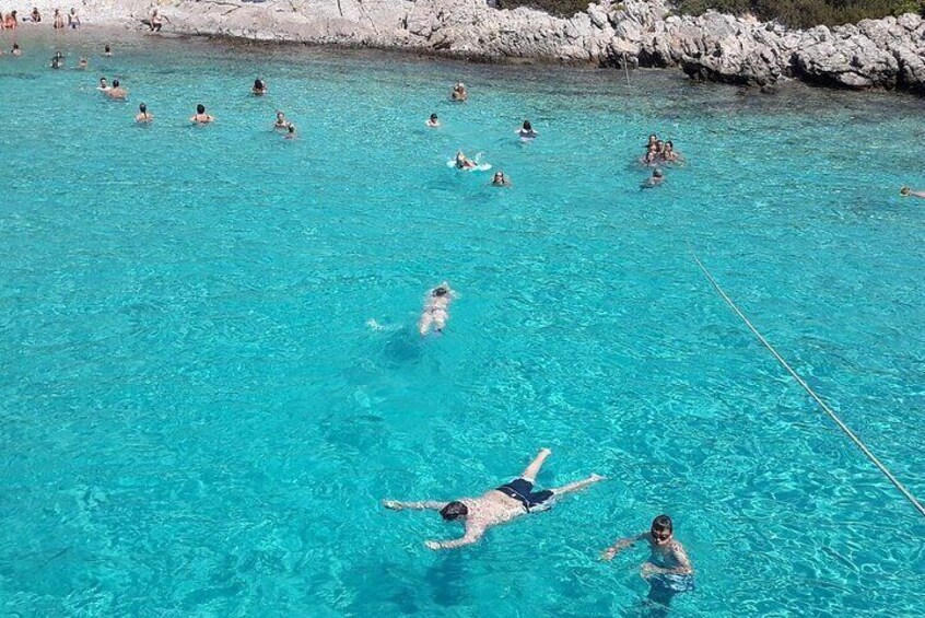 A group of people swimming in a clear blue pool surrounded by rocky terrain. 5
