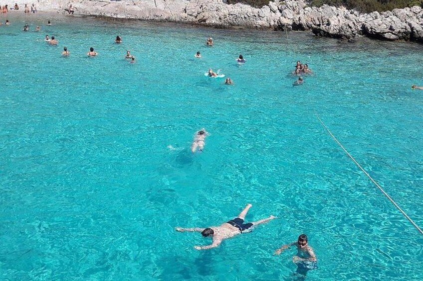 A group of people swimming in a clear blue pool surrounded by rocky terrain. 3