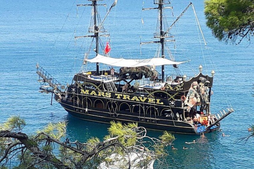 A large, black boat named 'MARS TRAVEL' with passengers and a flag, floating on a body of water. 2