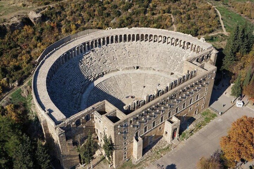 An ancient amphitheater with a semi-circular seating arrangement and a central stage. 1