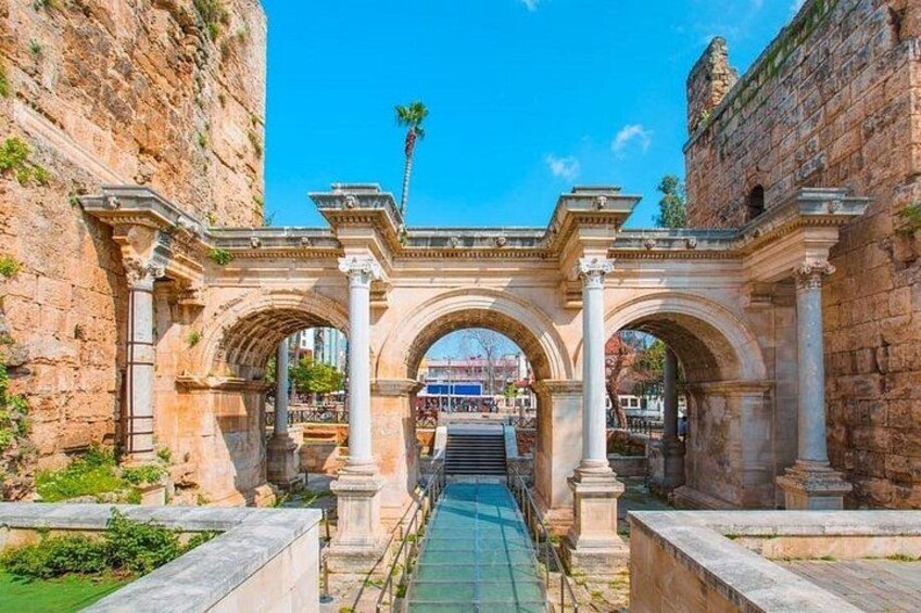 An ancient stone archway with columns, a paved pathway, and a clear blue sky. 3
