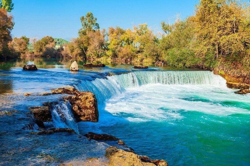 A waterfall, clear blue water, rocks, and trees. 2