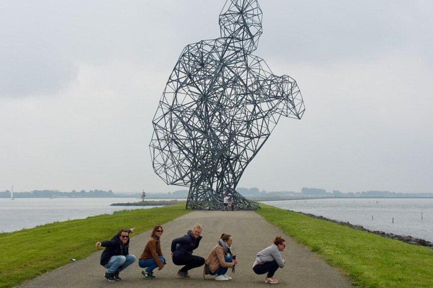 A geometric metal sculpture by artist Christo and Jeanne-Claude in a park with a body of water in the background. 2
