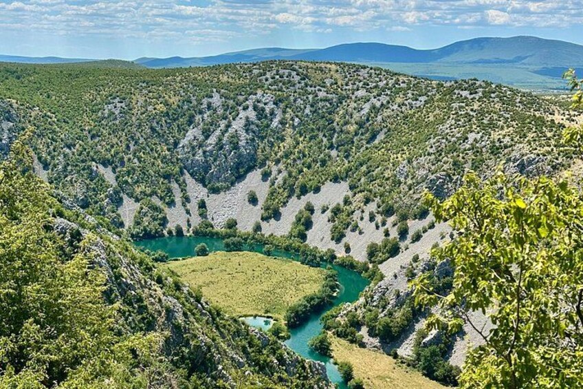 A valley with a river, surrounded by hills and dense vegetation. 1