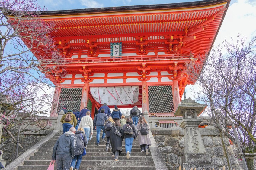 Un torii rojo tradicional japonés con gente subiendo los escalones. 5