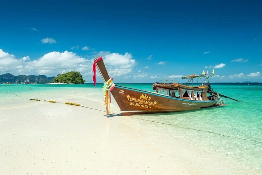A traditional wooden boat on a clear turquoise beach with a clear sky. 2