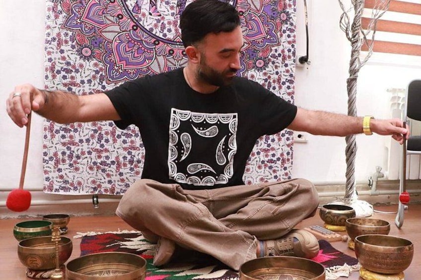 A person sitting on the floor surrounded by bowls and a stick. 1