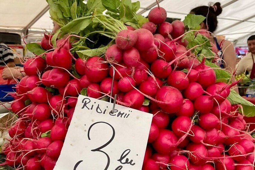 A pile of red radishes with a price tag. 5